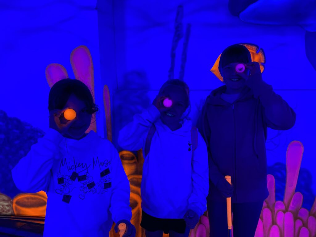 group of young carers holding neon golf balls over their eyes