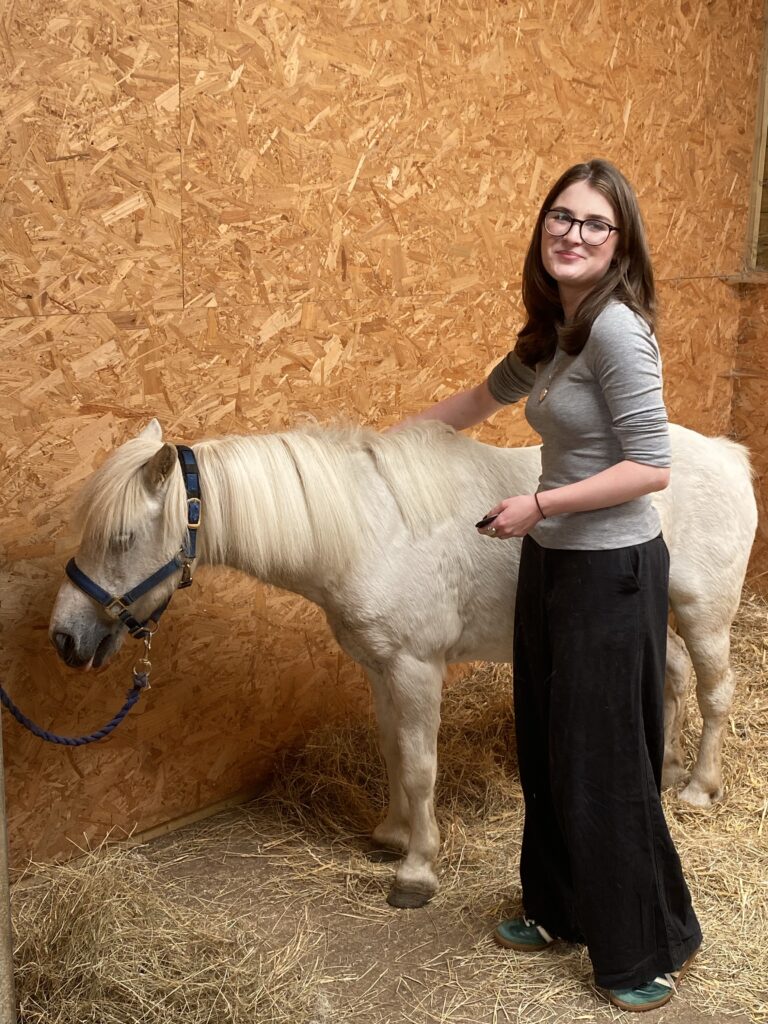 white horse in a barn with a women