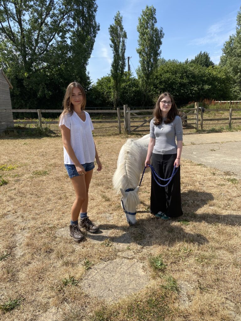 two young carers in a field with a white horse