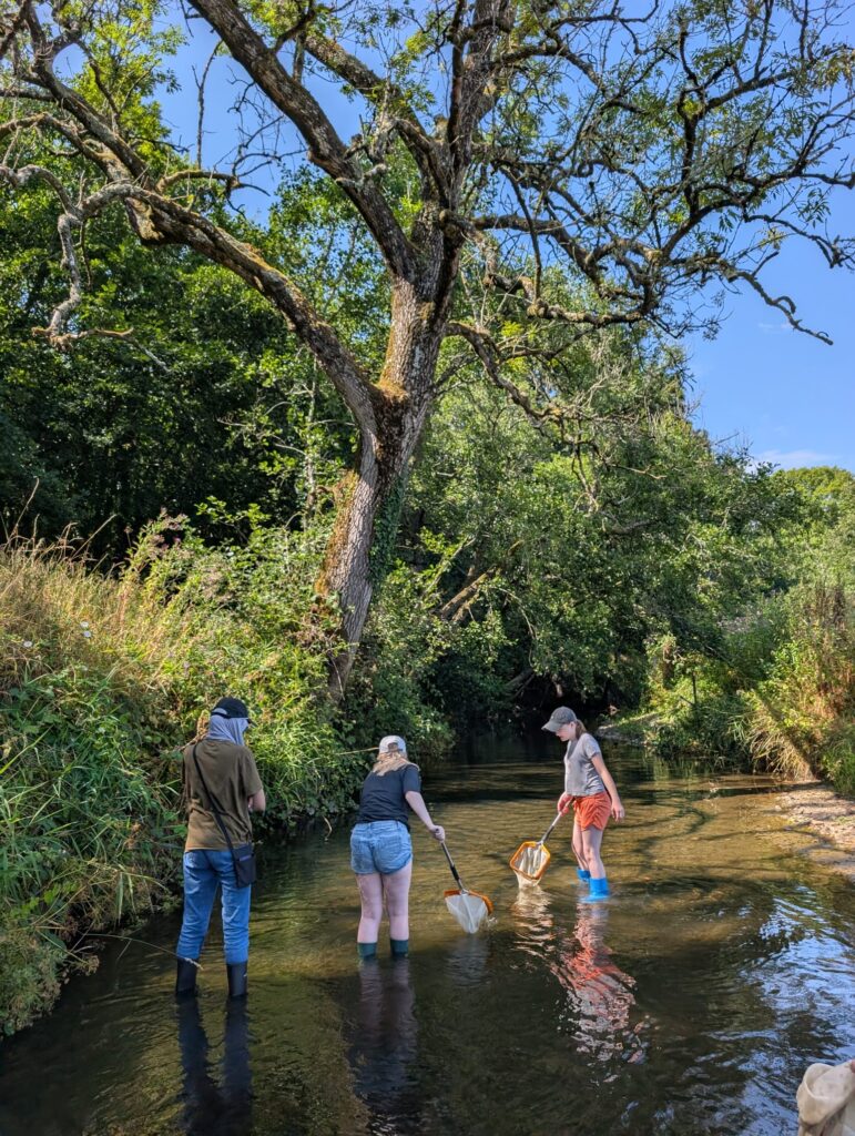 young people walking down a river in the british countryside